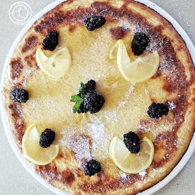 Dutch Pancake on a large plate, with lemon slices, blackberries, and mint