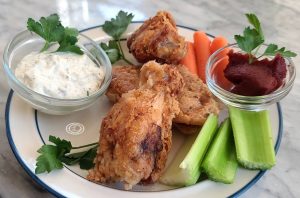 Chicken Wings on a plate with celery, carrots, and ranch.
