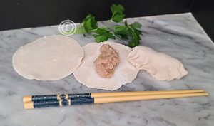 3 wrappers one plain, one with meat in the center, one wrapped potsticker