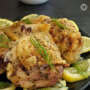A close up of Swedish Lemon Dill Chicken on a plate with lemon slices and dill weed.