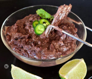 A bowl with a potato masher to mash the beans.