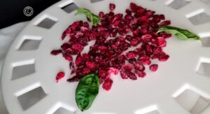 Dried berries on a white plate with sprigs of basil