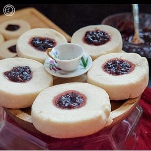 A close up of a small plate of 5 Gluten-Free Swedish Jam cookies with a small trinket tea cup and saucer.