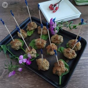 Gluten-Free Moroccan Kefta on a platter with toothpicks in them. Flowers and appetizer plates in the background.