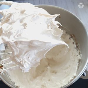A close-up of a whipper over a bowl of Homemade Marshmallow Fluff.