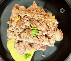 A stack of three Pineapple Pancake Bars on a plate with a piece of fresh pineapple