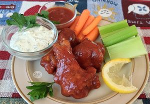 BBQ Chicken Wing Sauce on chicken wings with celery, carrots, ranch, and BBQ sauce.