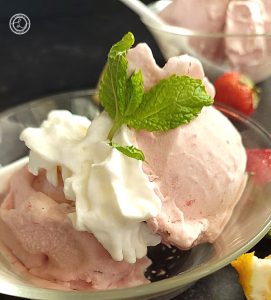 Dairy-Free Strawberry Ice Cream in a small bowl with fresh berries, whipped cream, and sprig of mint.