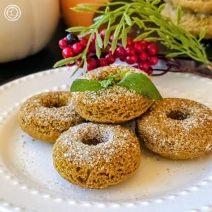Gluten-Free Harvest Pumpkin Donuts a plate of 5 donuts with pumpkins, berries, and leaves in the background.