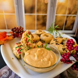 Pumpkin Glaze with a big bowl of glaze. Glazed donuts behind it. Some with sprinkles. One donut broken in half.