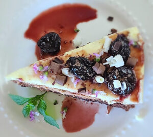Triple Chocolate Mousse Cake on a plate decorated with cherry sauce