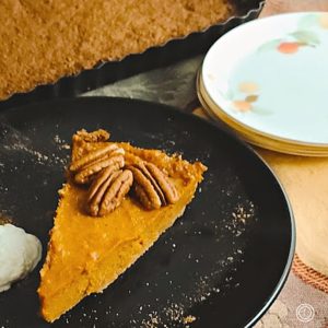A slice of Sweet Potato pie with a gingersnap crust in the background.