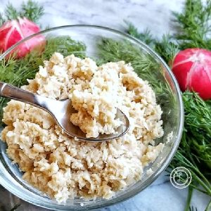 Horseradish in a bowl on a silver spoon, With fresh dill and radish surrounding it.
