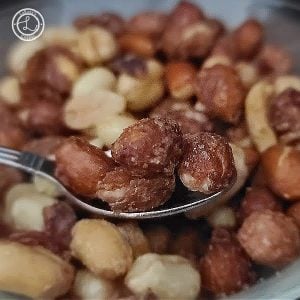 A close up of candied peanuts on a spoon.