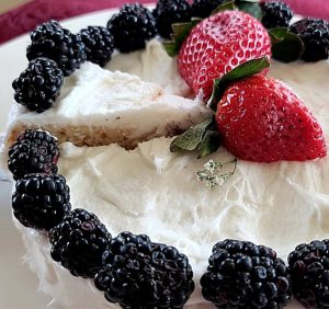 A quarter of vanilla cake with erimine frosting. Decorated with blackberries and strawberries.