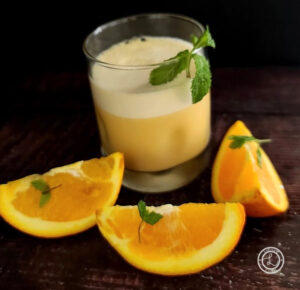 Protein Packed Orange Julius a glass with three slices of orange and sprigs omint.