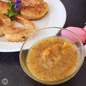 Orange Horseradish Marmalade in a bowl in front of a plate of coconut shrimp.