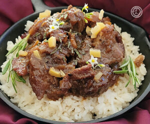 Greek Braised Rosemary Pork with Rosemary Sprigs, basil flowers, and preserved chopped lemons.