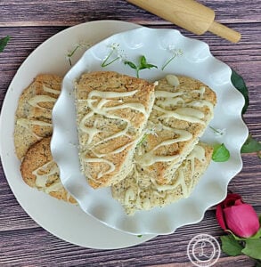 A picture of Gluten-Free Almond Poppyseed Scones on a cake platter with a platter of scones below.