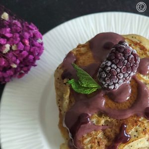 Refined Sugar-Free Blackberry Syrup in a corner view with flowers.