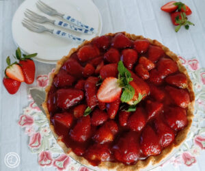 Gluten-Free Fresh Strawberry Pie on a white background with fresh strawberries, plates, and forks on a pretty table cloth.