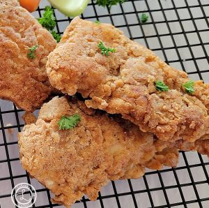 A close up of chicken strips cooling on a cooling rack.