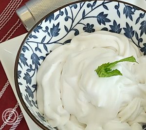 A close up of a big bowl of coconut milk whipped cream with a sprig of mint.