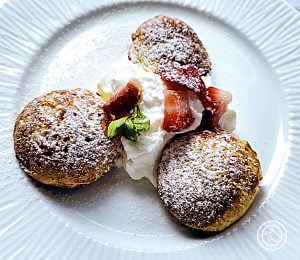 Gluten-Free Danish Pancakes on a plate with coconut whipped cream, chopped strawberries, and sprig of mint.