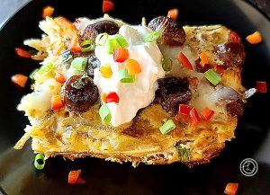 Gluten-Free Grilled Maple Sausage Casserole a slice of the casserole topped with sour cream, sausage, and chopped bell peppers on a black plate.