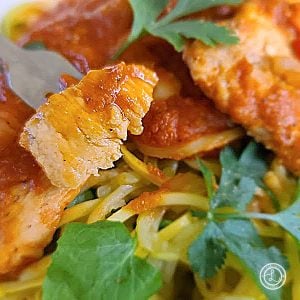 Moroccan Chicken and Peppers with a bite on a fork on top of a bed of zoodles.