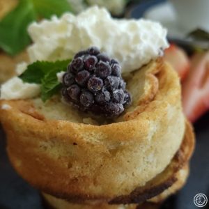 Gluten-Free Japanese Pancakes a very close up picture. Topped with coconut whipped cream, blackberry, and sprig of mint.