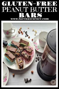 Gluten-Free Peanut Butter Bars on a plate surrounded by chocolate chips. Coffee cups, saucers, and French Press.