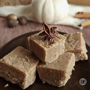 A small stack of Speculaas Spice Fudge on a plate. A star anise is in a piece of fudge to decorate.
