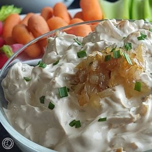 Dairy-Free French Onion Dip a bowl with caramelized onions on top. Carrots and celery behind it. Square photo.
