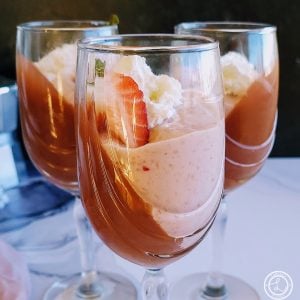 Close up of Three Strawberry Jello Pudding Parfaits with whipped cream and strawberry wedge.