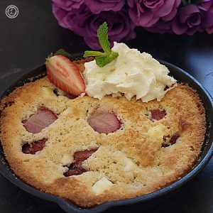 Gluten-Free Strawberry Cobbler with flowers behind it.