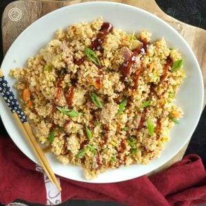 Babyback Rib Fried Rice in a serving bowl drizzled with BBQ sauce. On a cutting board, with a napkin, and chopsticks.