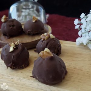 Maple Walnut Truffles 5 are shown. Behind is some flowers and a cupcake holder with shadow glass.