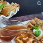 Homemade Pumpkin Spice Syrup Recipe Homemade Pumpkin Spice Syrup being poured onto crepes. A cake stand behind it with more crepes.