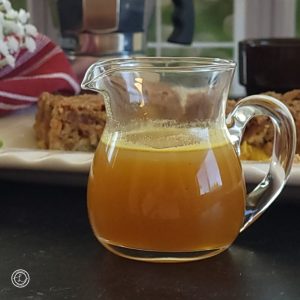 Refined Sugar-Free Pineapple Syrup in a small pitcher with an oven pancake in the background.
