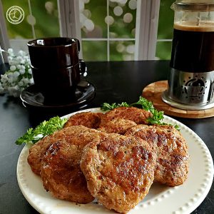 Ground Turkey Merguez Sausage on a plate with parsley, espresso cups, saucers, and a french press in the background.