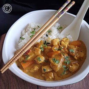 Gluten-Free Chicken Masala in a bowl with a soup spoon and chopsticks a top view.