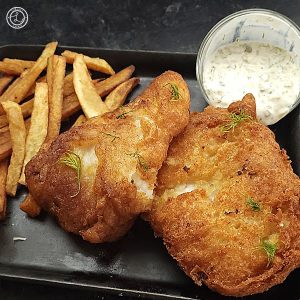 Gluten-Free Beer Battered Fried Fish. Two pieces on a plate with some fries and sauce.