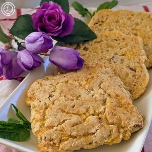 Gluten-Free Cheese Bacon Bread on a white platter with purple roses to the side.