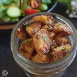 A small container of croutons with a salad poking out in the background.