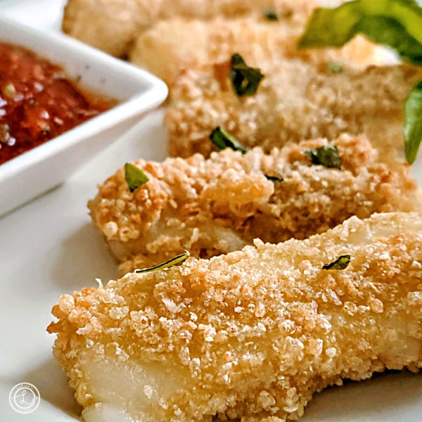 Gluten-Free Mozzarella Sticks Recipe Gluten-Free Mozzarella Sticks a square photo of cheezy melting out of a stick with marinara sauce and a sprig of basil.